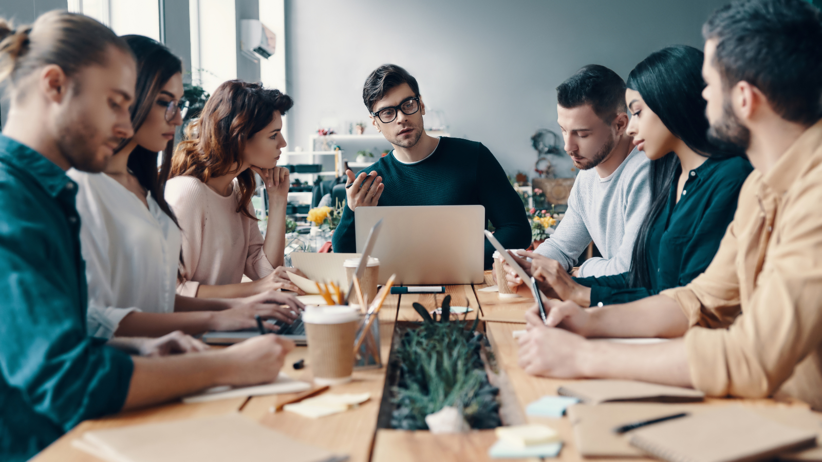 A team of office workers sitting at a conference room table having a discussion.